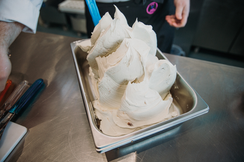 The image shows a member of the Gelato Academy dispensing ice cream into a tray to demonstrate building a base for gelato.